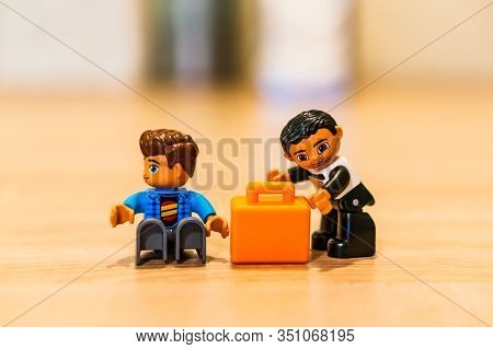 Poznan, Poland - February 16, 2020: Lego Duplo Thief Trying To Steal A Orange Suitcase From A Sittin