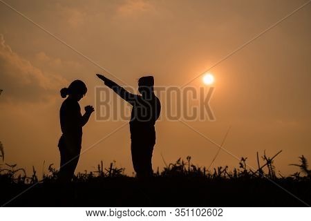 Silhouette Of Two Teen Girls Praying To God With The Bible.