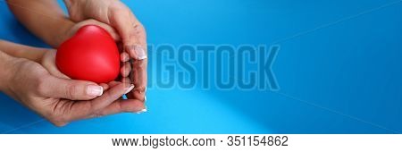 Mother And Daughter Hold Red Heart Against Blue Background Closeup. Happy Childhood Concept