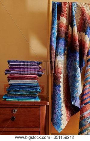 Stack Of Fabriсs And Quilt Made In The Bargello Style On Yellow Wall Background
