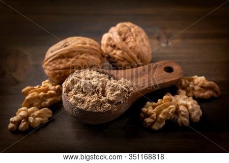 Walnut flour in the wooden spoon and whole seeds