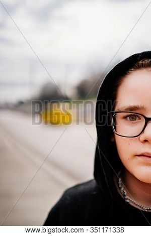 Gender Of The Face Portrait Of A Teenager In Glasses And Black Clothes With A Hood On The Street