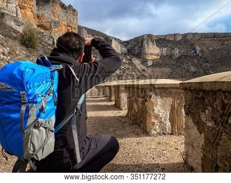 Photographer With A Blue Bag Crouching In The Middle Of A Sandy Path Taking A Picture In The Middle 