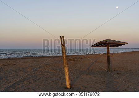 Caspian Sea With Beach And  Wooden Beach Umbrella With Moon In The Evening.