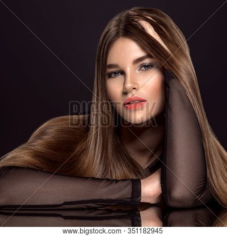 Woman with beauty long brown hair. Fashion model with long straight hair. Fashion model with a smokey makeup. Pretty woman with living coral color lipstick on lips. Living coral.