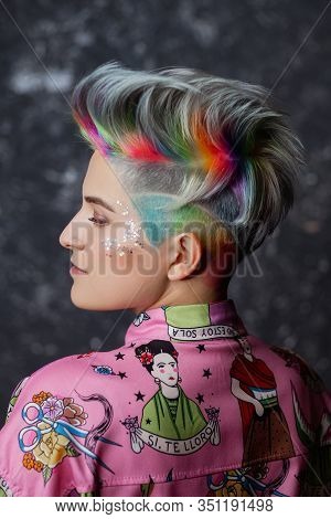 Portrait Of A Young Beautiful Girl In A Pink Shirt On A Gray Background With Dyed Hair. Short Haircu