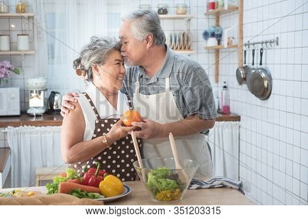 Senior Couple Having Fun In Kitchen With Healthy Food - Retired People Cooking Meal At Home With Man