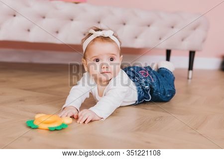 Baby Play With Teether In Mouth. Happy Cheerful Kid Girl Playing On The Floor.