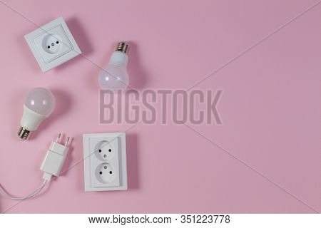 White Electrical Power Sockets, Power Plugs, Light Lamp Bulbs On Light Pink Background. Top View