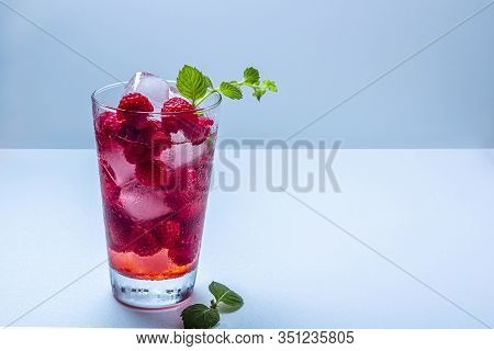 Raspberry Alcoholic Cocktail With Liqueur, Vodka, Ice And Mint On A Blue Background. Raspberry Mojit