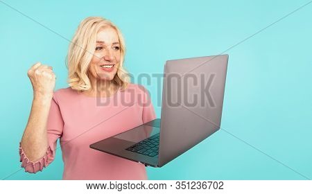 Portrait Of Happy Exited Abult Lady With Laptop Isolated Over The Blue Studio.