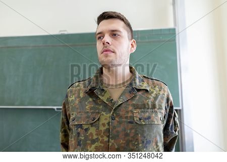 German Soldier Stands In A Classroom . German Word Bundeswehr, Means German Army.