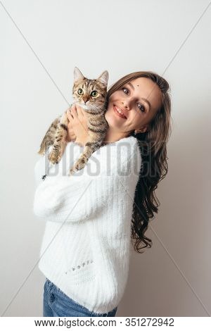 Girl In A White Sweater Hugs A Gray Cat On A White Background.