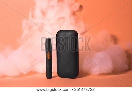 Iqos Electronic Cigarette In Smoke On An Orange Background.