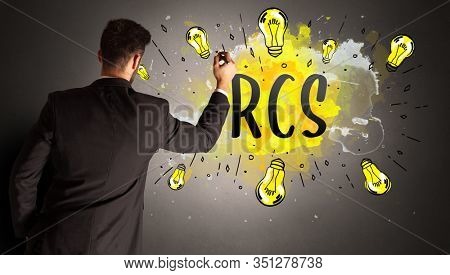 businessman drawing colorful light bulb with RCS abbreviation, new technology idea concept