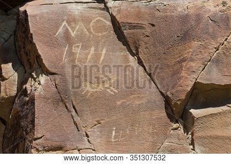 Modern Graffiti That Is Over A Hundred Years Old On A Sandstone Rock With A Small Petroglyph Carving