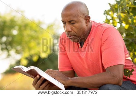 African American Man Praying And Reading The Bible.