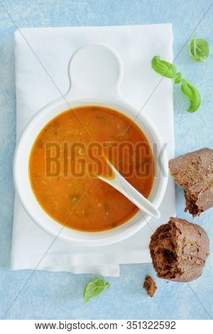 Zesty Homemade Tomato Basil Soup With Dark Rye Mini Loaf With Basil Garnish In Flat Lay Composition.