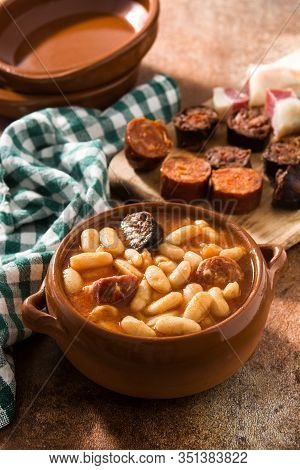 Typical Spanish Fabada Asturiana In Crockpot On Wooden Table