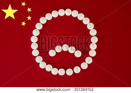 Sad Smiley Face Made Of White Tablets And Pills On Red Background Of The Chinese Flag, Top View. 201