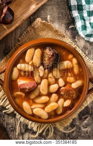 Typical Spanish Fabada Asturiana In Crockpot On Wooden Table. Top View
