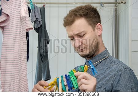 Portrait Of A Man About 30 Years Old With A Beard, Hangs His Clothes On A Clothesline, Leads A Bache