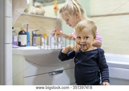 Two Cute Adorable Blond Caucasian Siblings Washing Face And Cleaning Tooth With Toothbrush At Bathro