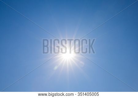 Shining Sun On Clear Blue Sky. Lens Flare Of Sunlight On Blue Sky Background. Bright Sun On Blue Sky