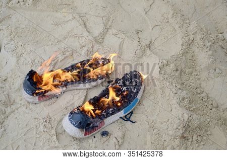 Burning Sports Sneakers Or Gym Shoes On Fire Stand On Sandy Beach Coast. Athlete Burned Out. Physica