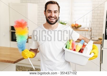 Image of young cheerful smiling positive man househusband indoors.