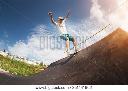 Portrait Of A Young Skateboarder Doing A Trick On His Skateboard On A Halfpipe Ramp In A Skate Park 