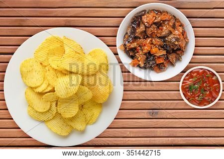 Potato Chips On A White Plate With Vegetarion Salad. Chips On A Orange Wooden Background Top View.