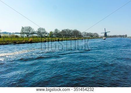 Waterways And Canals In North Holland With Boats And View On Traditional Dutch Mill, Spring Landscap