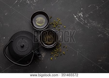 Traditional Asian Tea In Black Cast Iron Vintage Teapot With Two Cups On Dark Stone Table And Dry Gr