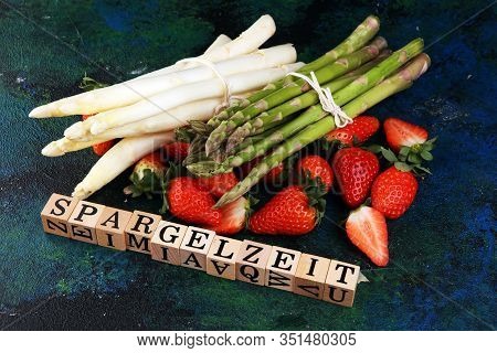 White And Green Asparagus With Strawberries On Rustic Background With Spargelzeit Wooden Letter.