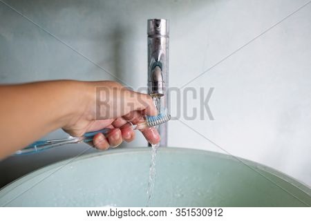 Woman's Left Hand Washing Toothbrush On Green Washbasin, Water Flowing From Faucet, Bathrooom Concep