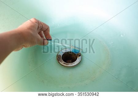 Woman's Left Hand Holding Toothbrush For Cleaning Green Washbasin, Bathrooom Cleaning Concept