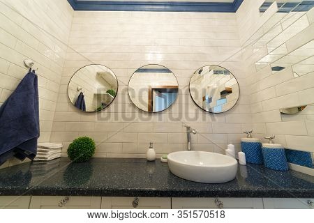 Bathroom In A Residential Building. Dressing Table With Mirrors. Sink With Candles And Soap. A Towel