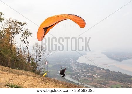 Paragliding In The Sky. Paraglider  Flying Over Landscape From Beautiful View Mekong River At Wat Ph