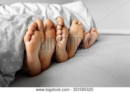 A Young Family, A Family Wakes Up In The Morning,feet On The Bed,healthy Legs Of A Young Family,fami