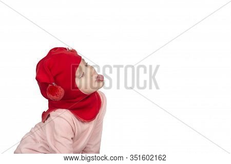 Funny Little Girl In Red Wool Winter Balaclava Or Knitted Cap Making Funny Faces. Gigl Showing Tongu