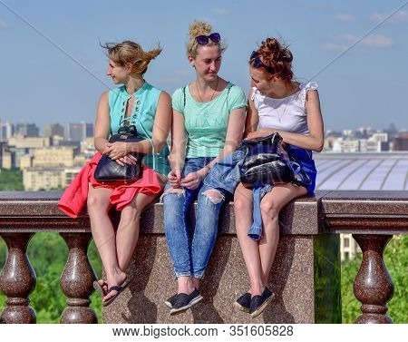 Russia, Moscow, May 2018. Three Girls Sit On The Parapet On Observation Deck Vorobyovy Gory . Popula