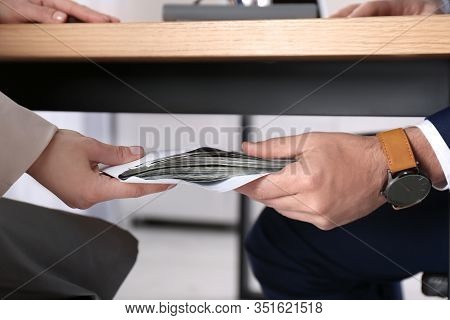 Woman Giving Bribe To Man Under Table In Office, Closeup