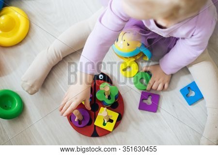 Girl Plays Toys In Living Room. Montessori Wooden Toy Folded Pyramid. Circle, Quadra, Triangle, Rect