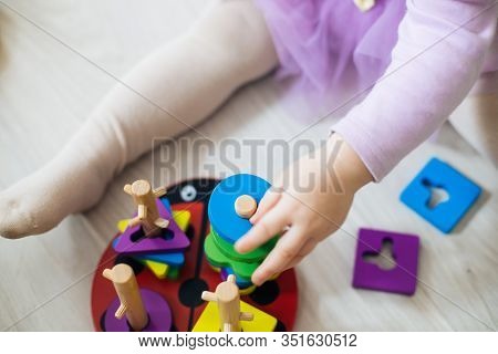 Girl Plays Toys In Living Room. Montessori Wooden Toy Folded Pyramid. Circle, Quadra, Triangle, Rect