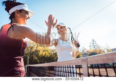 Women giving high five after a good and friendly match of tennis