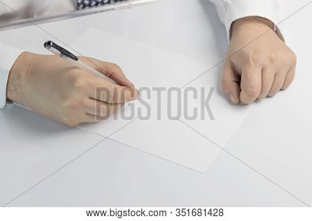Businessman Writes On A Sheet Of White Paper. Dressed In A Shirt And Tie. Close-up.