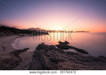 Long Exposure Image Of Sun Setting Over The Golden Sand Of Plage De Sainte Restitude Beach In The Ba