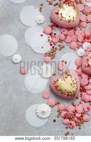Pink Hearts From Tempered Chocolate With Chocolate Drops, Meringues And Dried Berries On Grey Backgr
