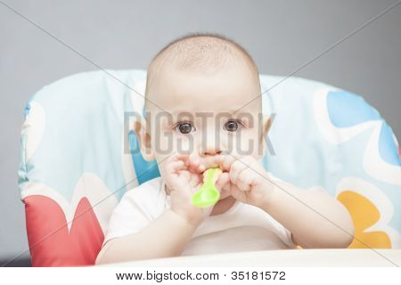 Ruhige Caucasian Infant In Stuhl mit kleinen Löffel